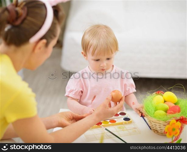 Mother and baby drawing on Easter eggs