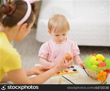 Mother and baby drawing on Easter eggs