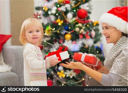 Mother and baby girl changing Christmas presents