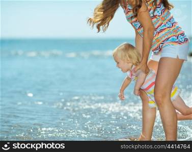 Mother and baby girl playing on sea coast