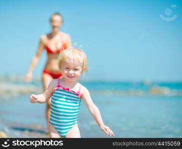 Mother and baby girl playing on sea shore