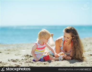 Mother and baby girl playing with sand on beach