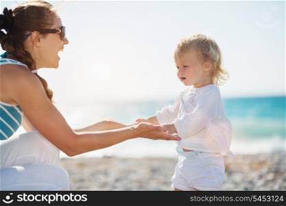 Mother and baby holding hands on beach
