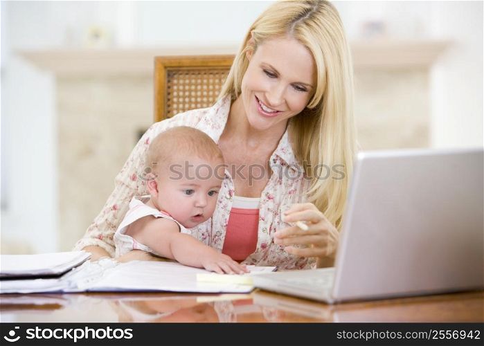 Mother and baby in dining room with laptop smiling
