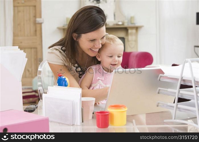 Mother and baby in home office with laptop