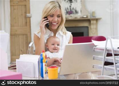 Mother and baby in home office with laptop and telephone
