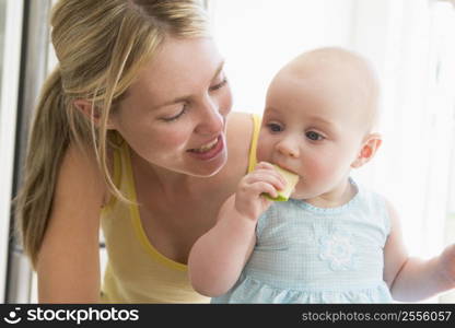 Mother and baby in kitchen eating apple