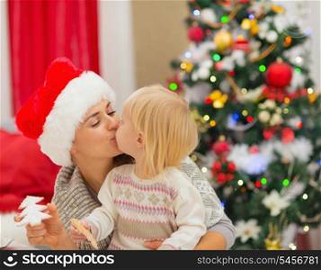 Mother and baby kissing near Christmas tree