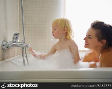 Mother and baby playing in bathtub