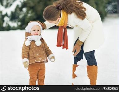 Mother and baby playing in winter outdoors
