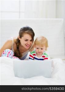 Mother and baby playing with laptop
