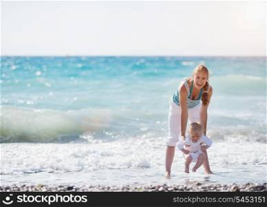 Mother and baby playing with sea waves