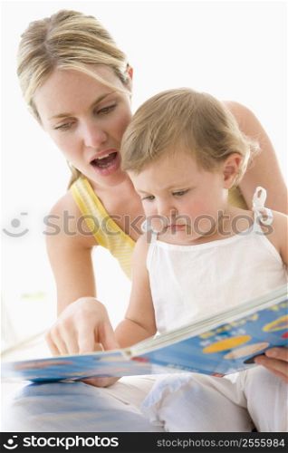 Mother and baby reading book indoors and pointing