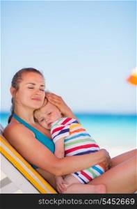 Mother and baby relaxing on sunbed on beach