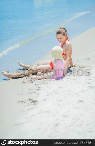 Mother and baby sitting on beach