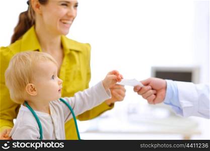 Mother and baby stretching for prescription in hand of pediatric doctor&#xA;