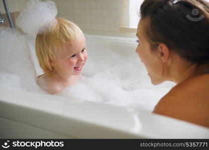 Mother and baby taking bath and playing with foam