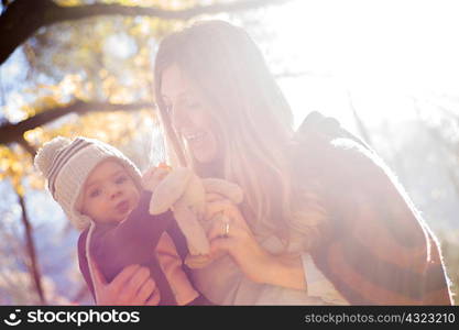 Mother and baby with cuddly toy in forest
