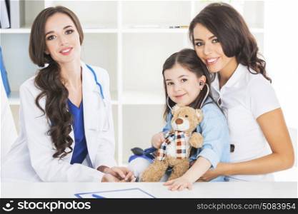Mother and child at pediatrician. Happy mother and child with teddy bear and stethoscope at pediatrician office