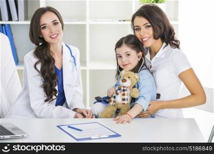 Mother and child at pediatrician office. Happy mother and child with teddy bear and stethoscope at pediatrician office