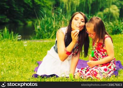 Mother and child blowing soap bubbles outdoor.. Mother and daughter child blowing soap bubbles outdoor. Parent and kid having fun in park. Happy and carefree childhood. Good family relations.