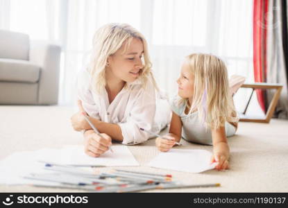 Mother and child draw lying on the floor. Parent feeling. Mother and child draw lying on the floor