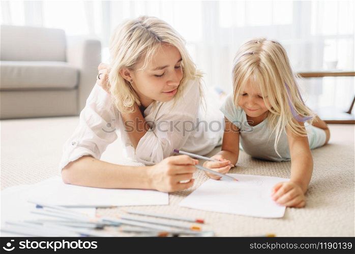 Mother and child draw lying on the floor. Parent feeling. Mother and child draw lying on the floor