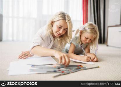 Mother and child draw lying on the floor. Parent feeling, togetherness