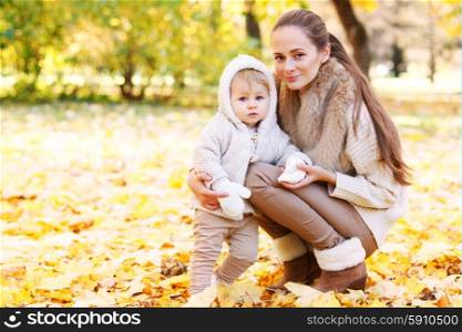 Mother and child in autumn park. Mother and child having fun in autumn park among yellow leaves