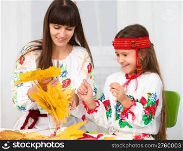 Mother and child in Ukrainian national cloth doing crafts