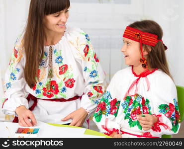 Mother and child in Ukrainian national cloth doing crafts