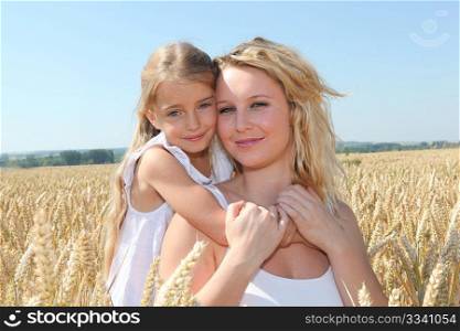 Mother and child in wheat field on sunny day