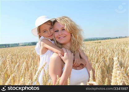 Mother and child in wheat field on sunny day