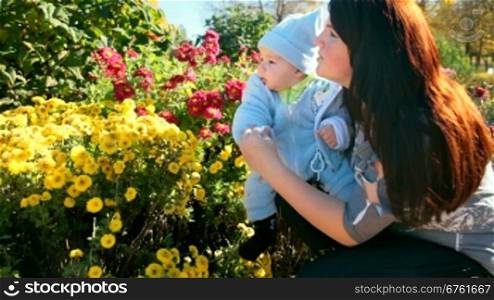 mother and child near a flowerbed in a sunny autumn day