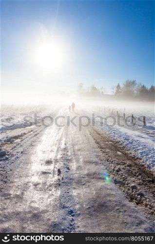 Mother and child on foggy snow road near farm