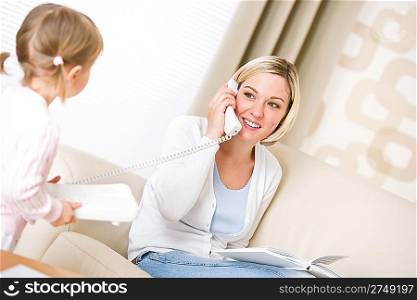 Mother and child - on the phone in living room with book