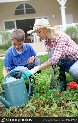 Mother and child planting flowers in house garden