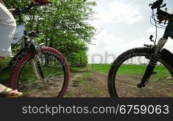 Mother and child riding bikes down a country lane, rear view
