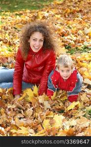 mother and child sit among fallen leaves