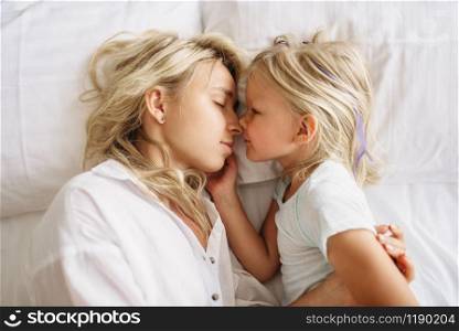 Mother and child sleeps on the bed at home, top view. Parent feeling, togetherness, happy times