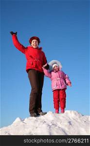 mother and child stand on the top of the snowy hill