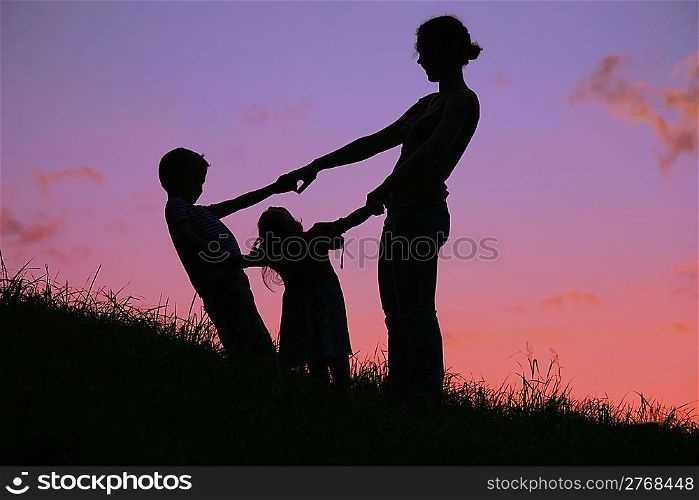 mother and children are held for the hands on the sunset