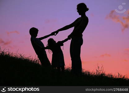 mother and children are held for the hands on the sunset