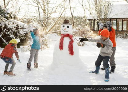 Mother And Children Building Snowman In Garden