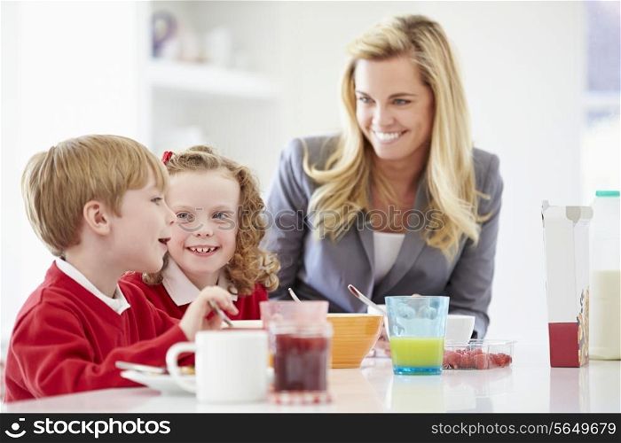 Mother And Children Having Breakfast In Kitchen Together