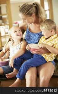 Mother And Children Having Breakfast Sitting On Kitchen Counter