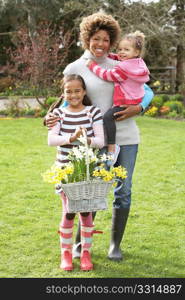 Mother And Children Holding Basket Of Daffodils In Garden