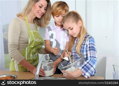 Mother and children in kitchen preparing cake
