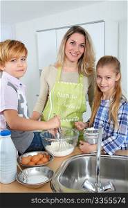 Mother and children in kitchen preparing cake