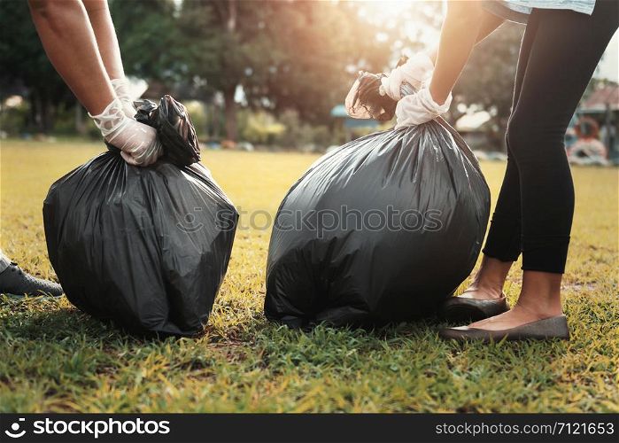mother and children keeping garbage black bag at park in morning light
